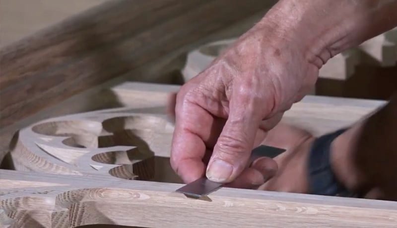 close up of hand measuring wood carving