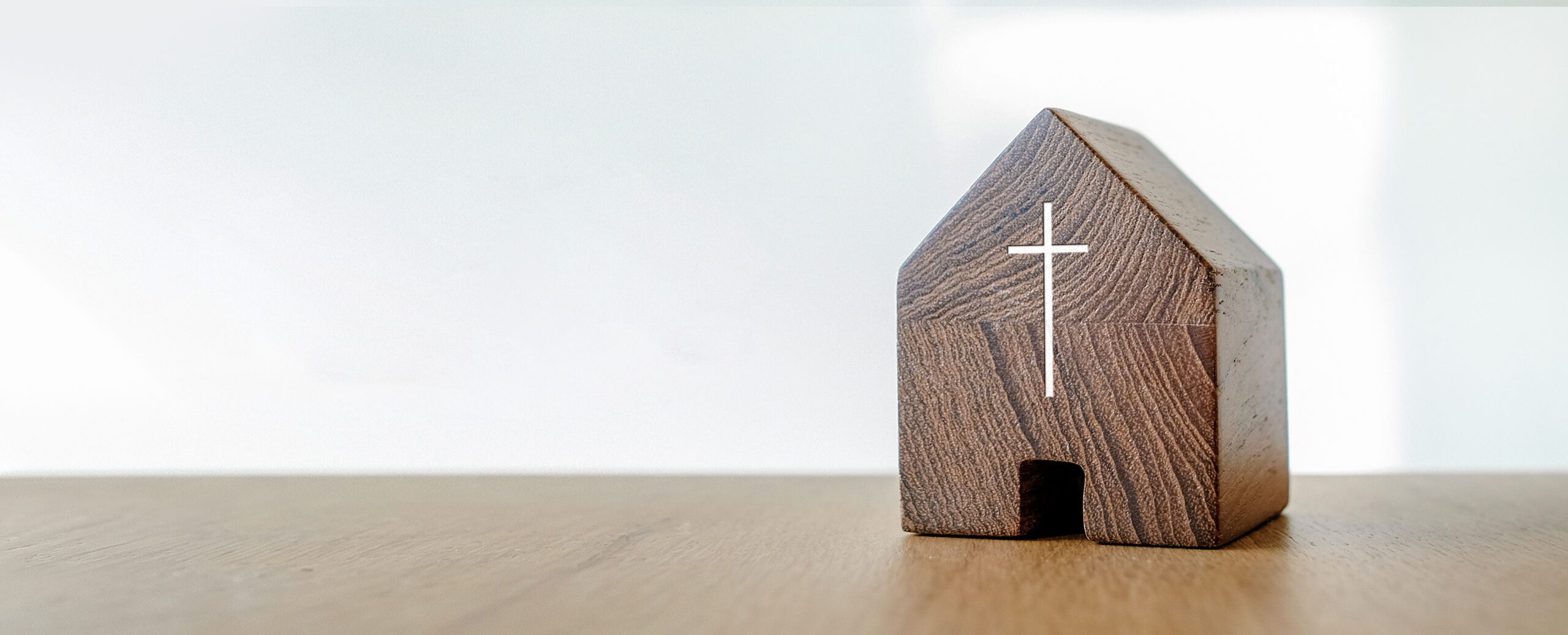 A small wooden block with a door cut out and a silver cross to make it resemble a church.