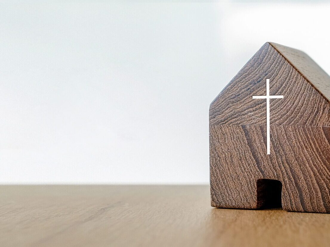 A small wooden block with a door cut out and a silver cross to make it resemble a church.