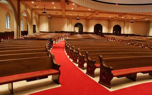 Curved church pews with red fabric on benches.