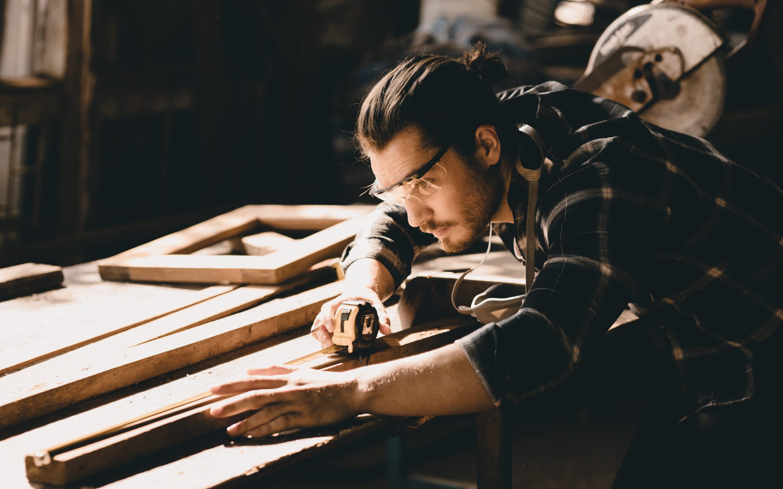 A carpenter measures a piece of wood.