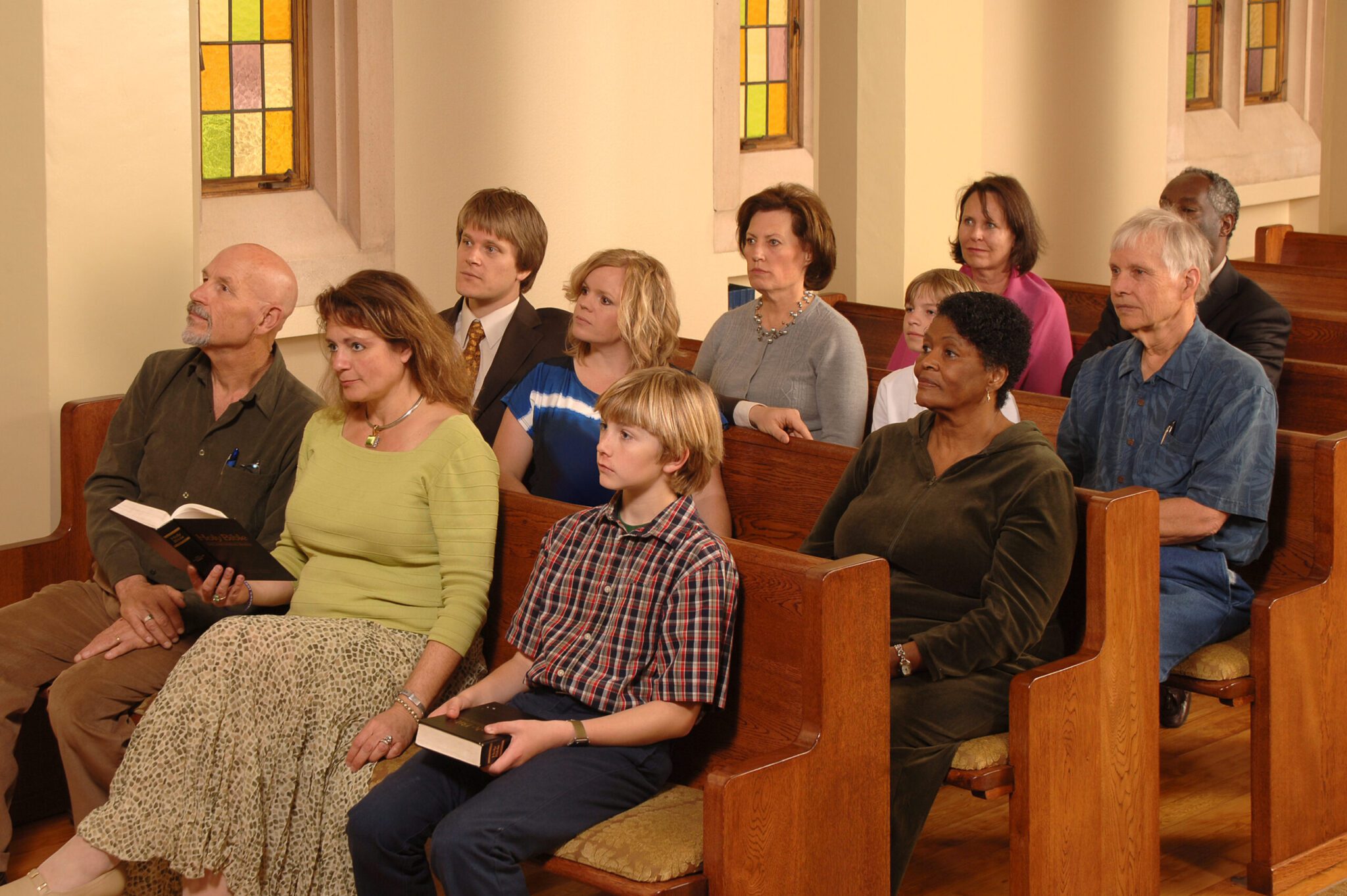 A congregation sitting in church pews, looking uncomfortable.