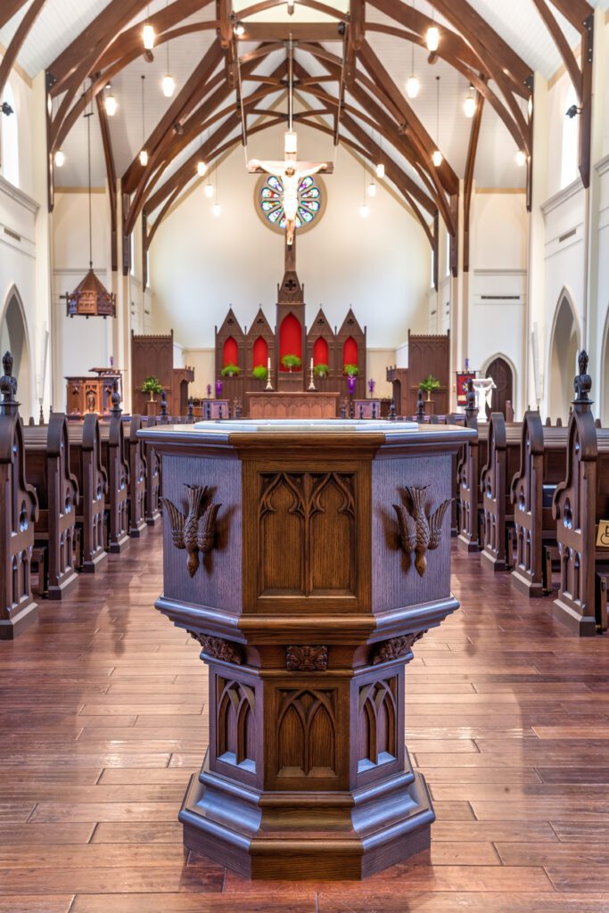A baptismal font sits in the middle of church pews.
